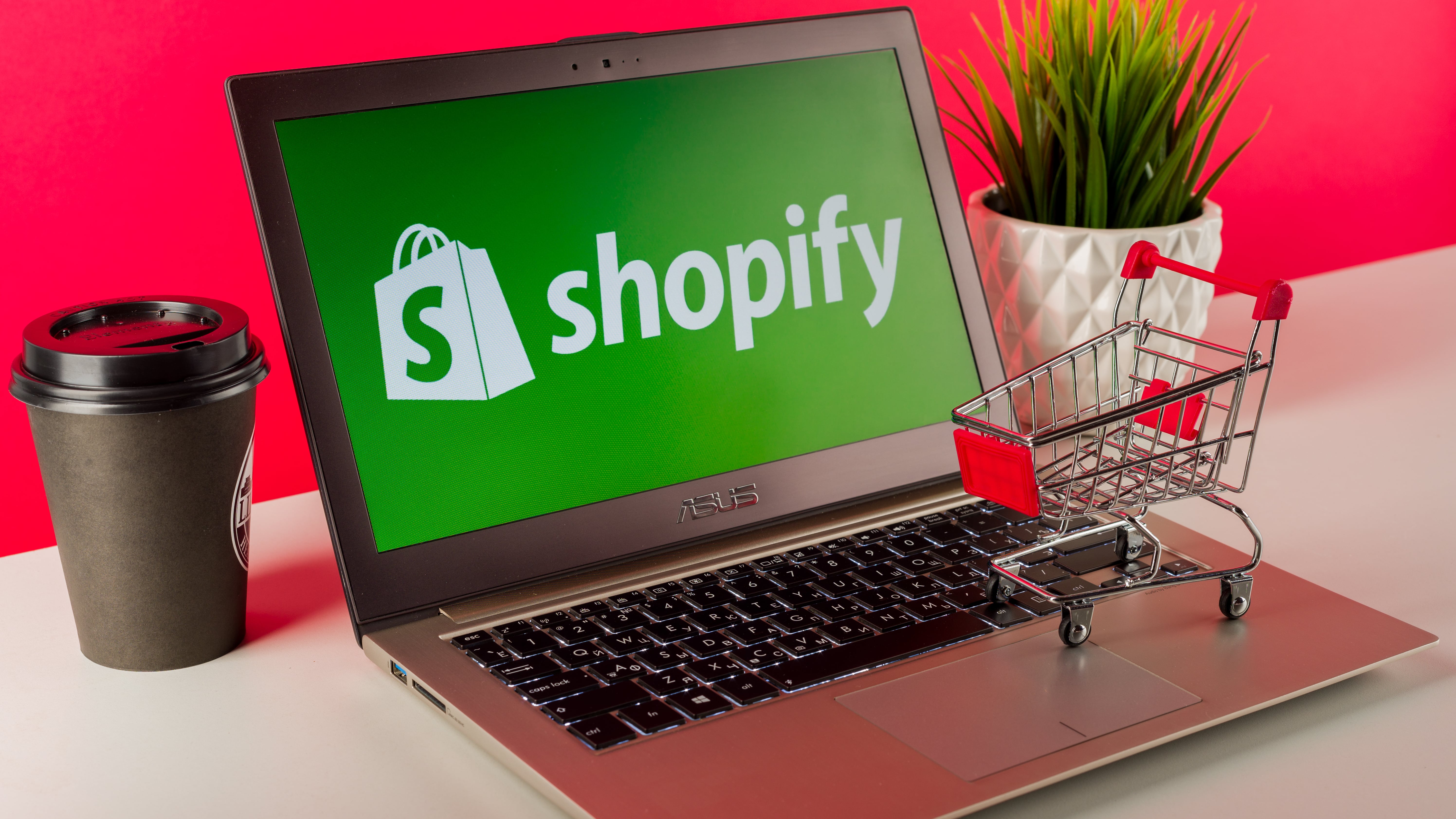 Shopify logo displayed on a modern laptop on desk with cart