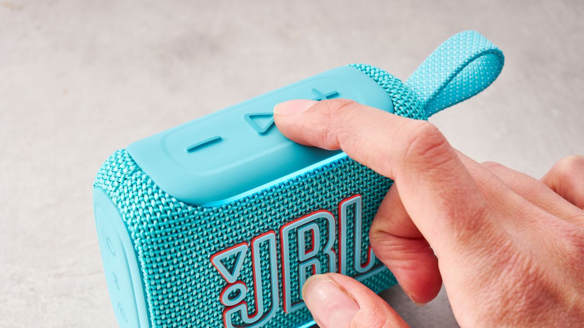 Finger pressing the play button on the JBL Go 5