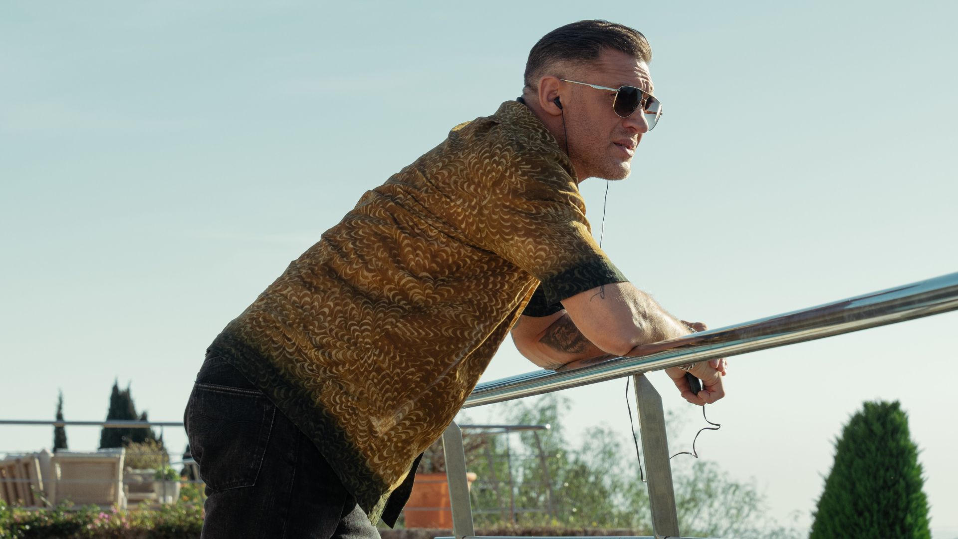 Tom Hardy leans on a metal railing
