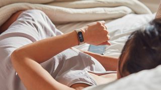 Woman in bed looking at Fitbit
