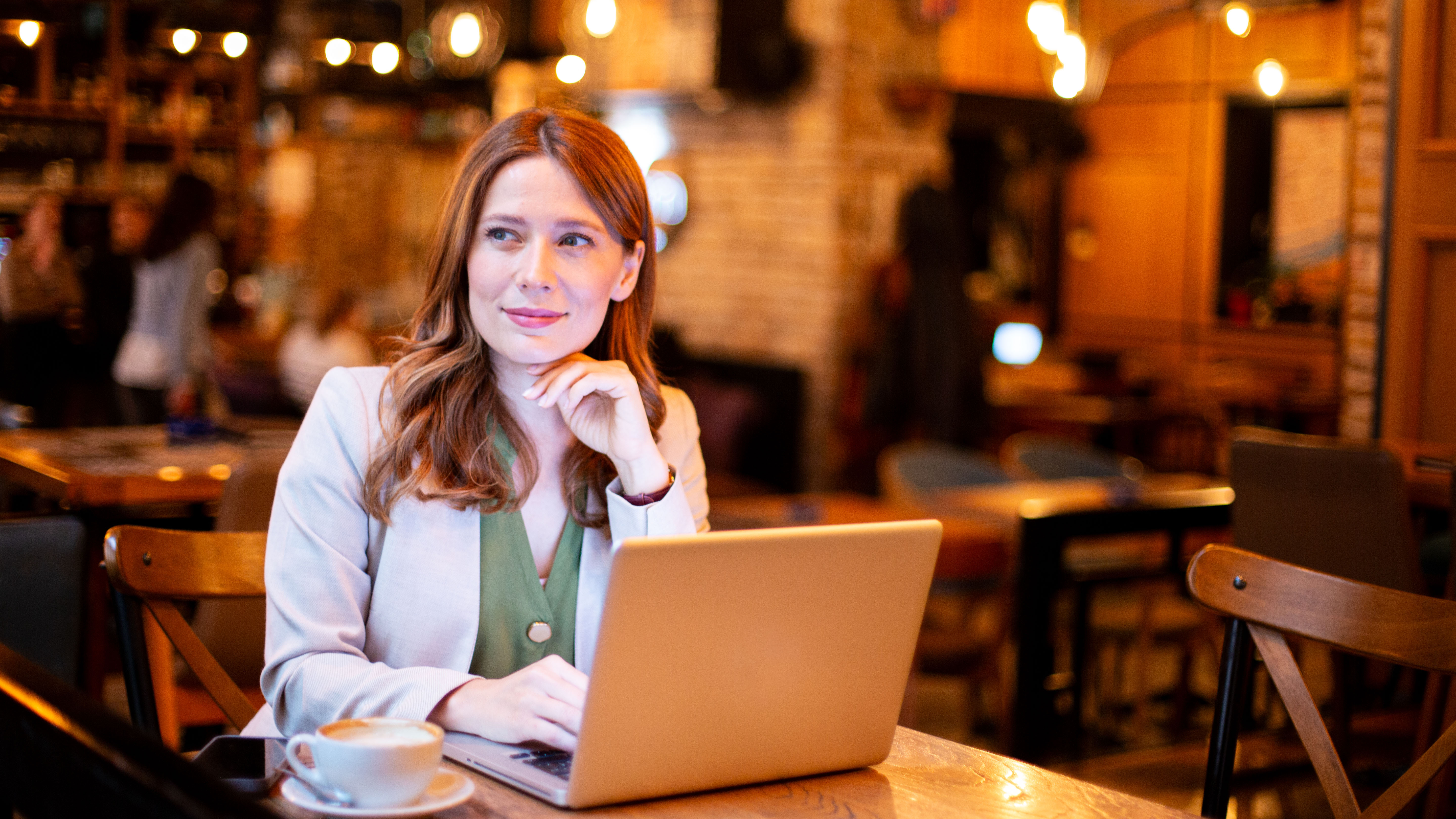 Woman focusing on work in a coffee shop, using a laptop and drinking coffee