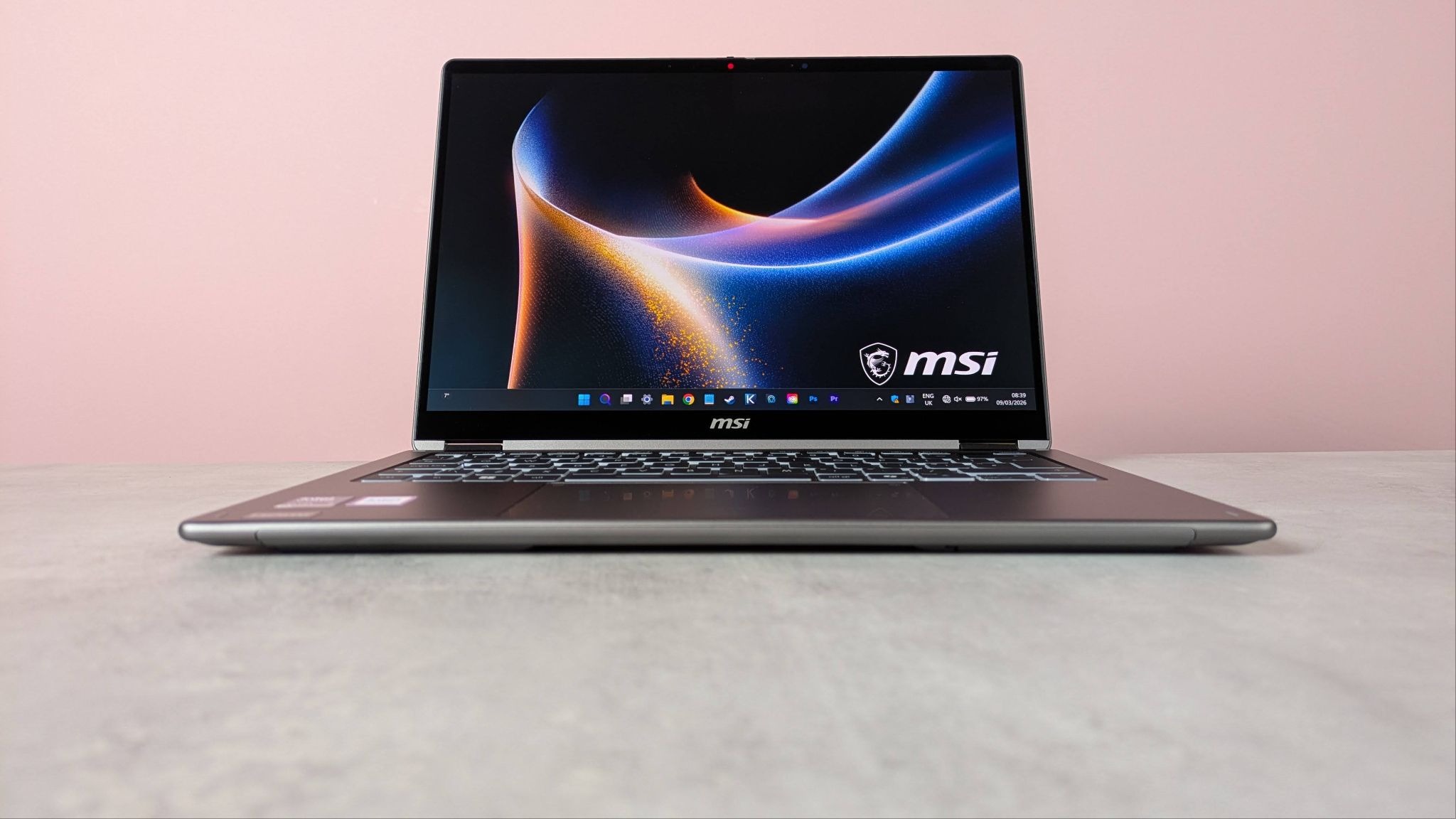 Front view of MSI Prestige 14 Flip AI+ open on desk with pink wall in background
