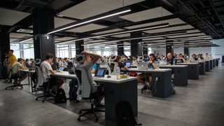 Office with many desks and workers at computers