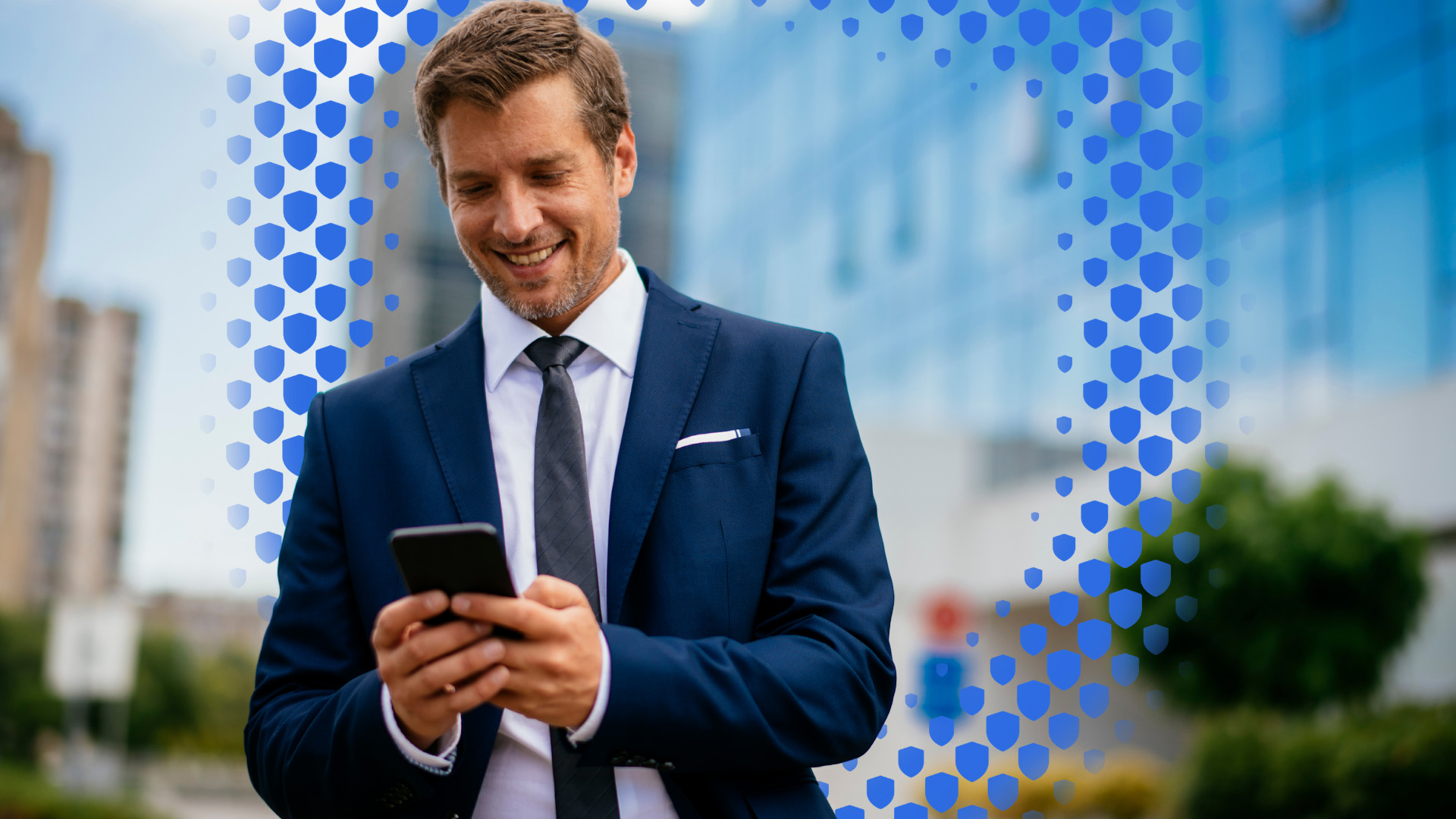 A man in a blue suit looks happily at his phone
