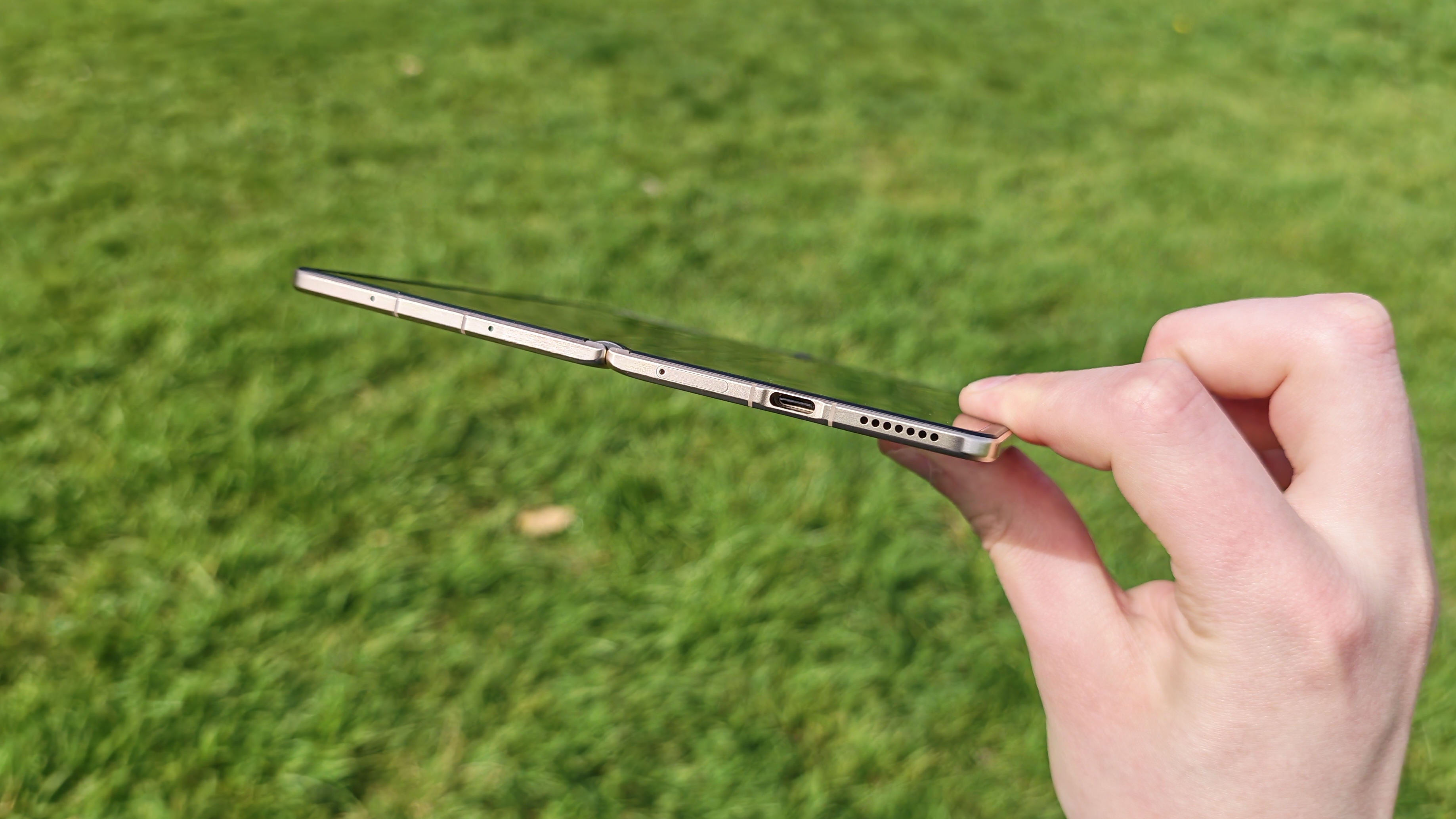 The  Honor Magic V6 being held in a sunny field. 