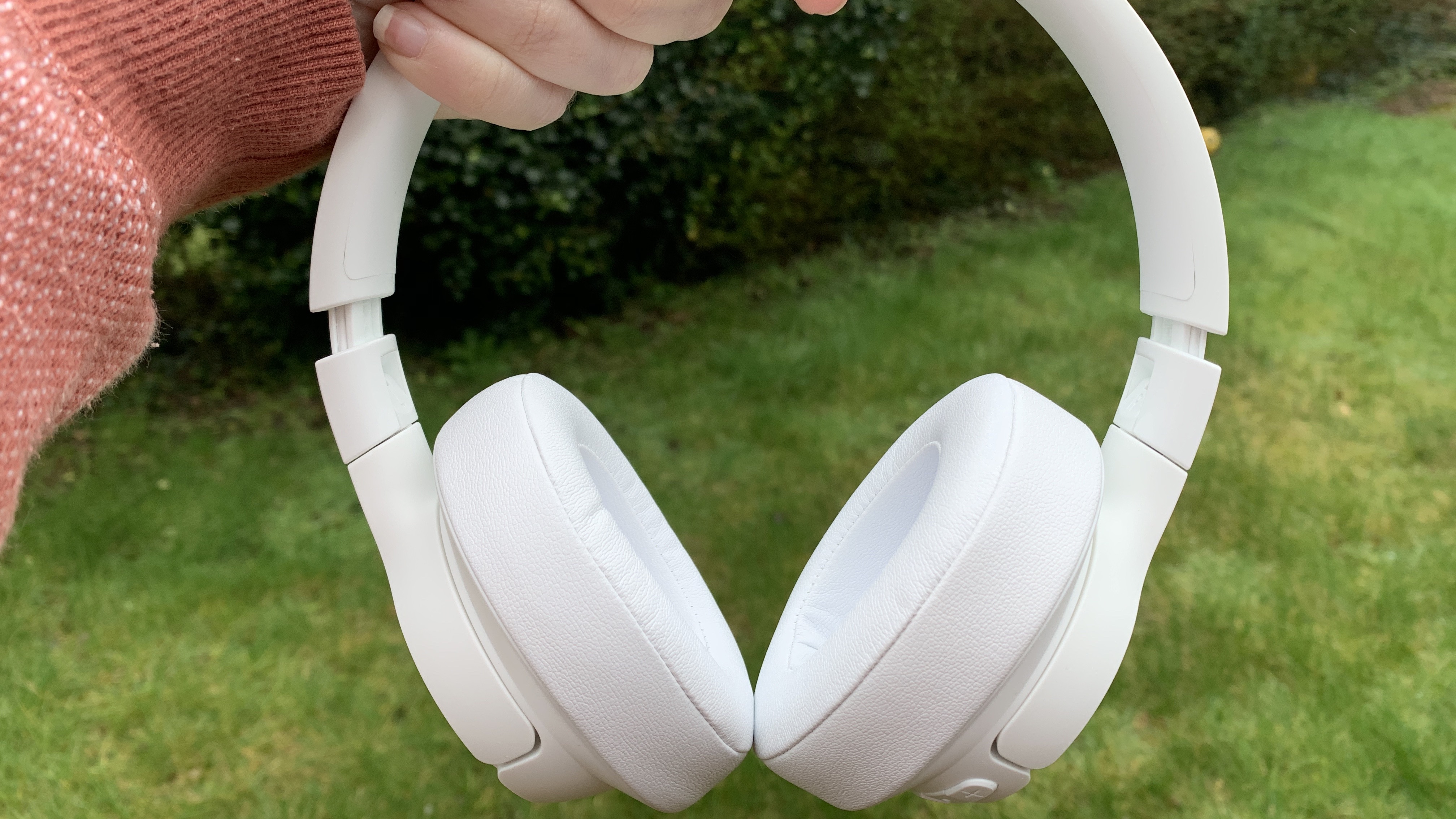 A close up of the jbl tune 750btnc on-ear headphones in white against a grass background