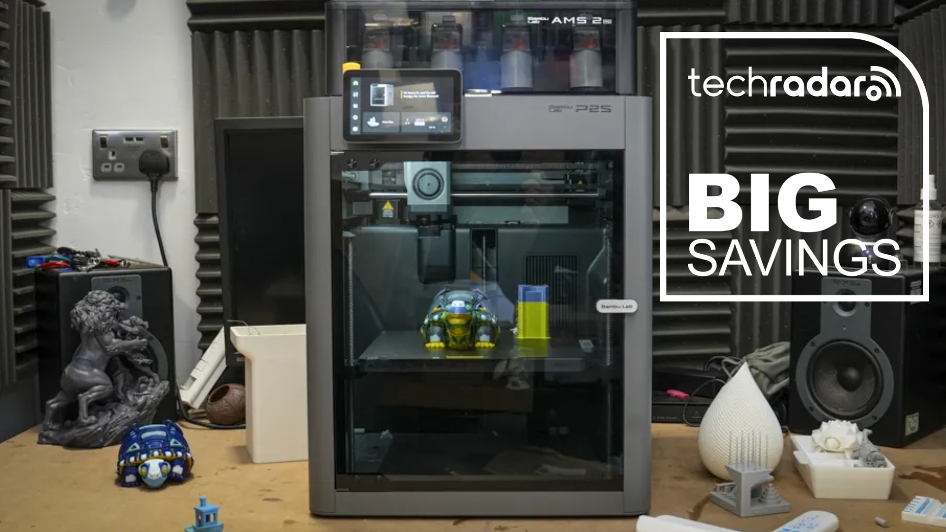 A Bambu Lab P2S in our workshop, with a blue diamond TechRadar badge reading 'Big Savings'