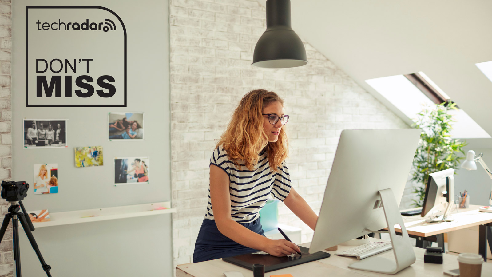 Woman standing at a desktop computer and drawing on a tablet in a loft-style space. The TechRadar logo and "Don't Miss" text are in the top left in black.