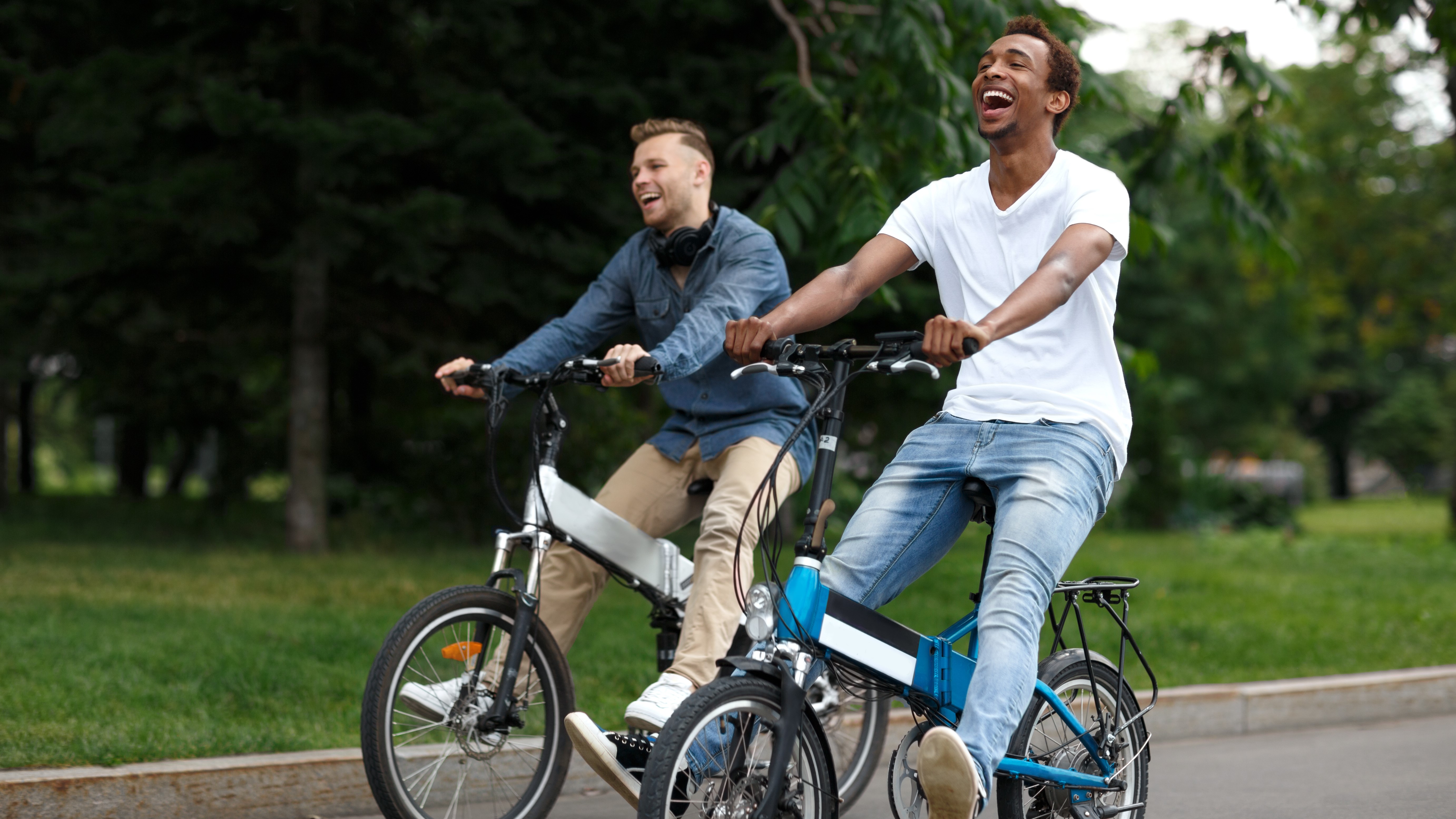 Two young men riding e-bikes in a park