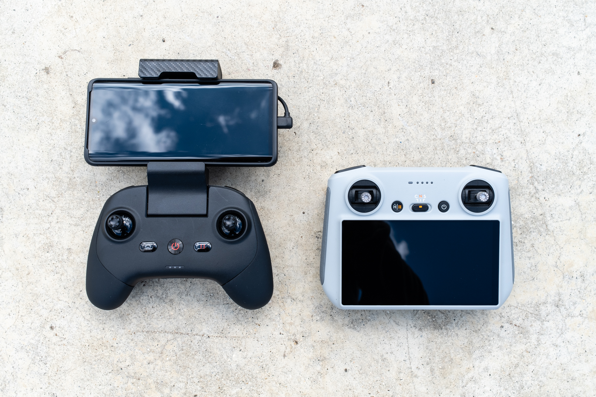 The Autel EVO Nano+ drone and its controller next to the DJI Mavic Mini 3 Pro and its controller on a concrete surface