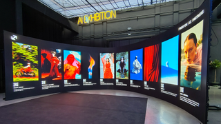A wraparound screen showing multiple AI images under a banner reading 'AI Exhibition' during Freepik Upscale Malaga
