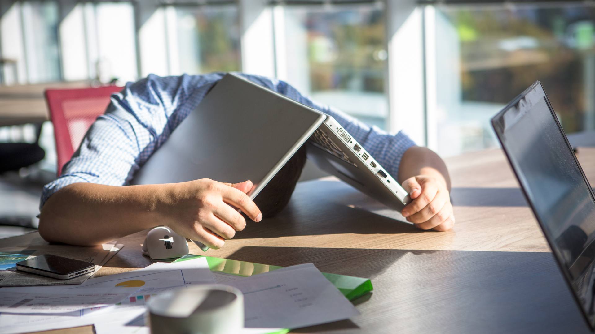 Man hiding head under Windows 11 laptop
