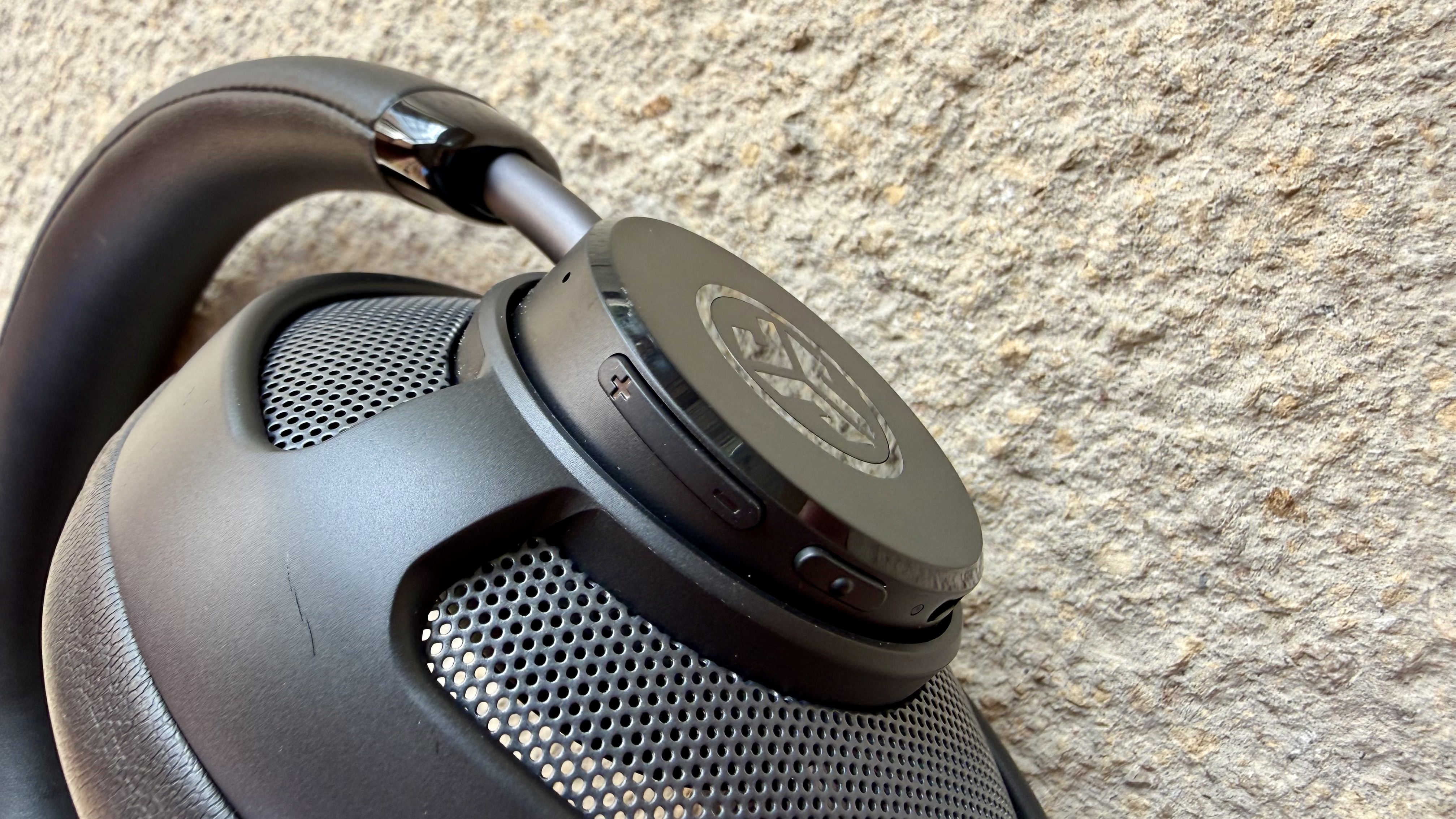 The jlab jbuds open wireless headphones close up of their buttons on a stone surface
