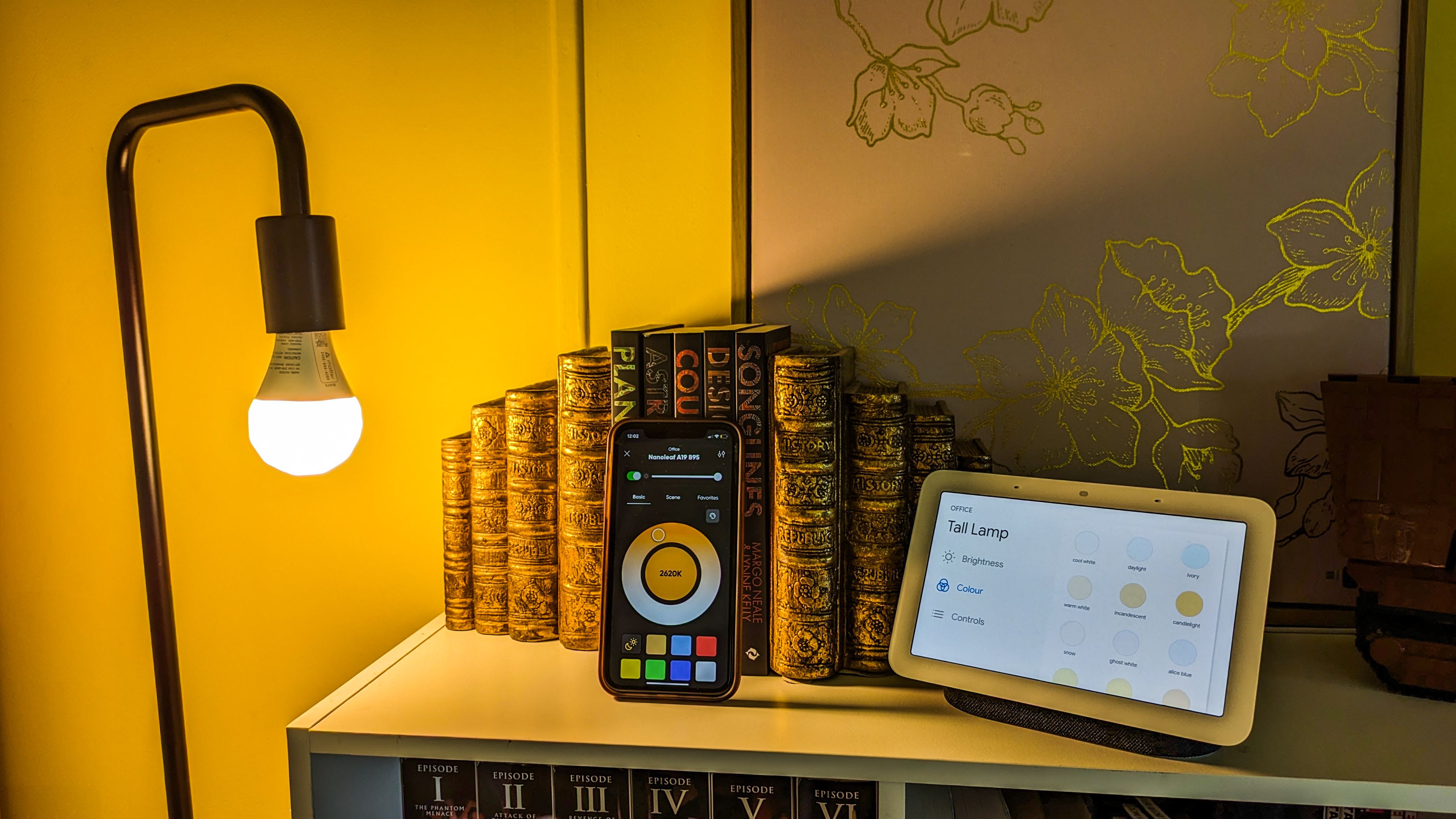 Nanoleaf Essentials smart bulb next to iPhone XR and Google Next Hub 2 showing the difference between colour selection