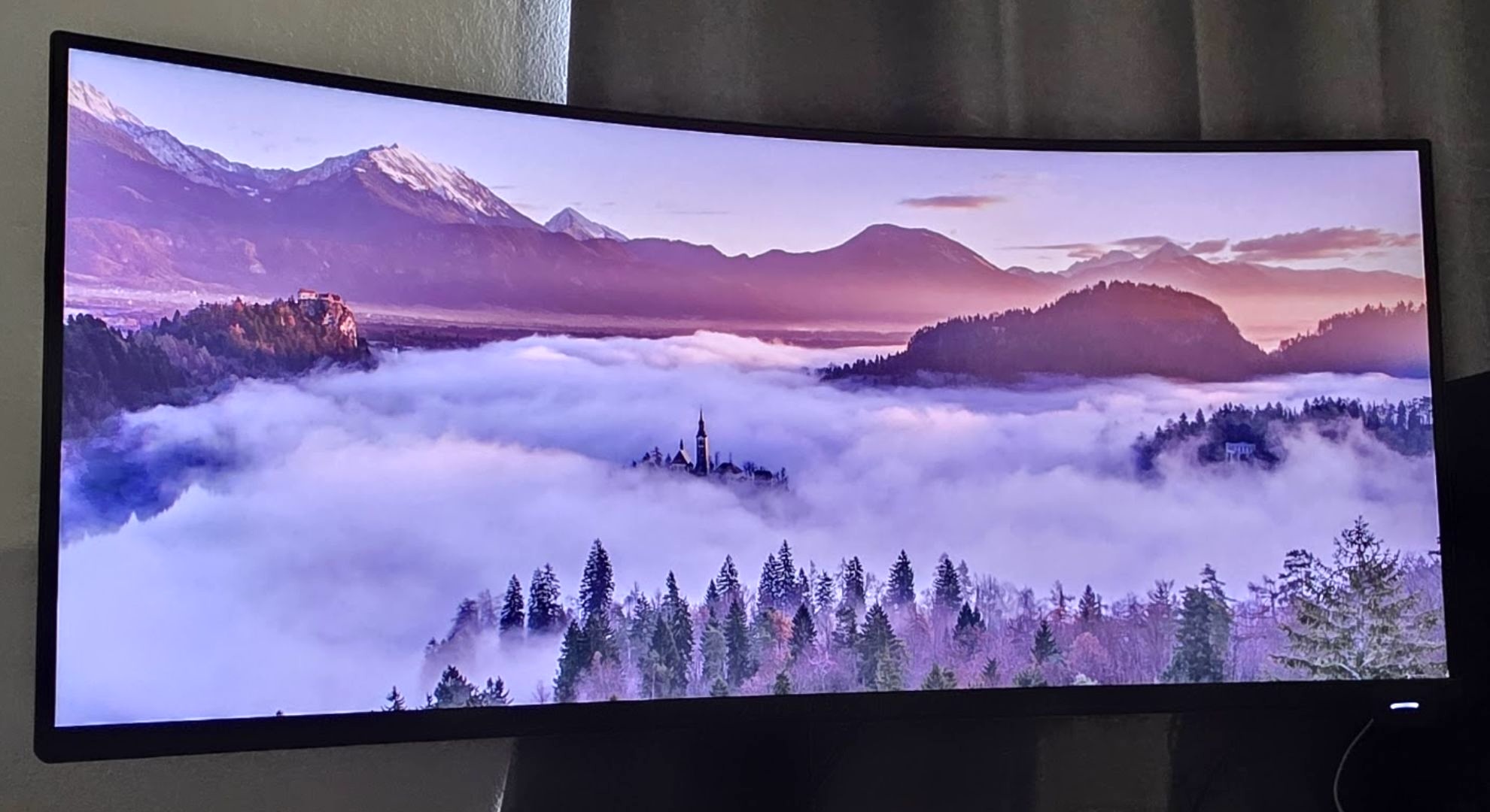 An ultra-wide monitor displaying an image of a valley of fog