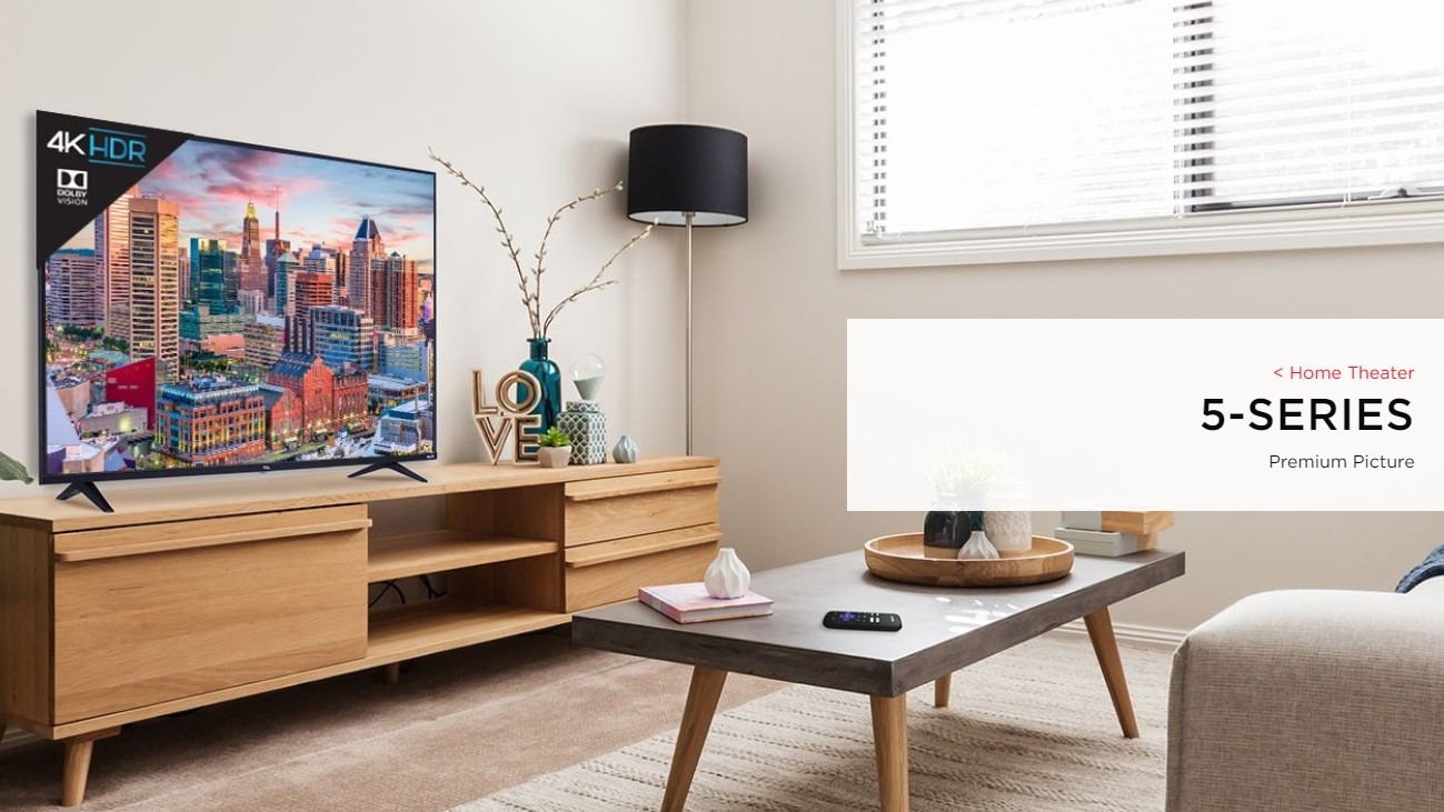 TCL 5-Series 4K TV in a living room on a TV stand while displaying a city scape scene