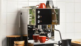 A Seattle Coffee Gear espresso machine with a coffee cup on the shelf