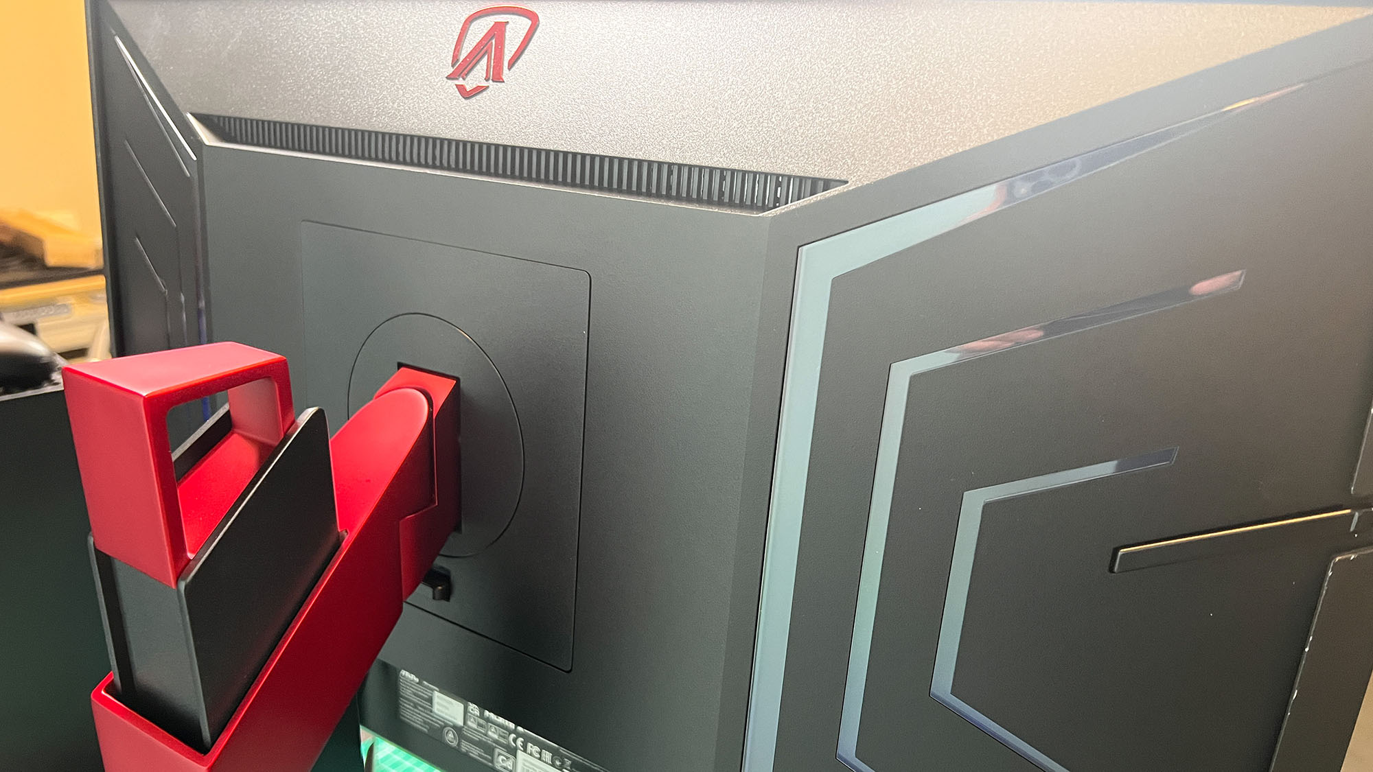 An AOC Agon Pro AG274QZM on a black desk with a green deskmat underneath