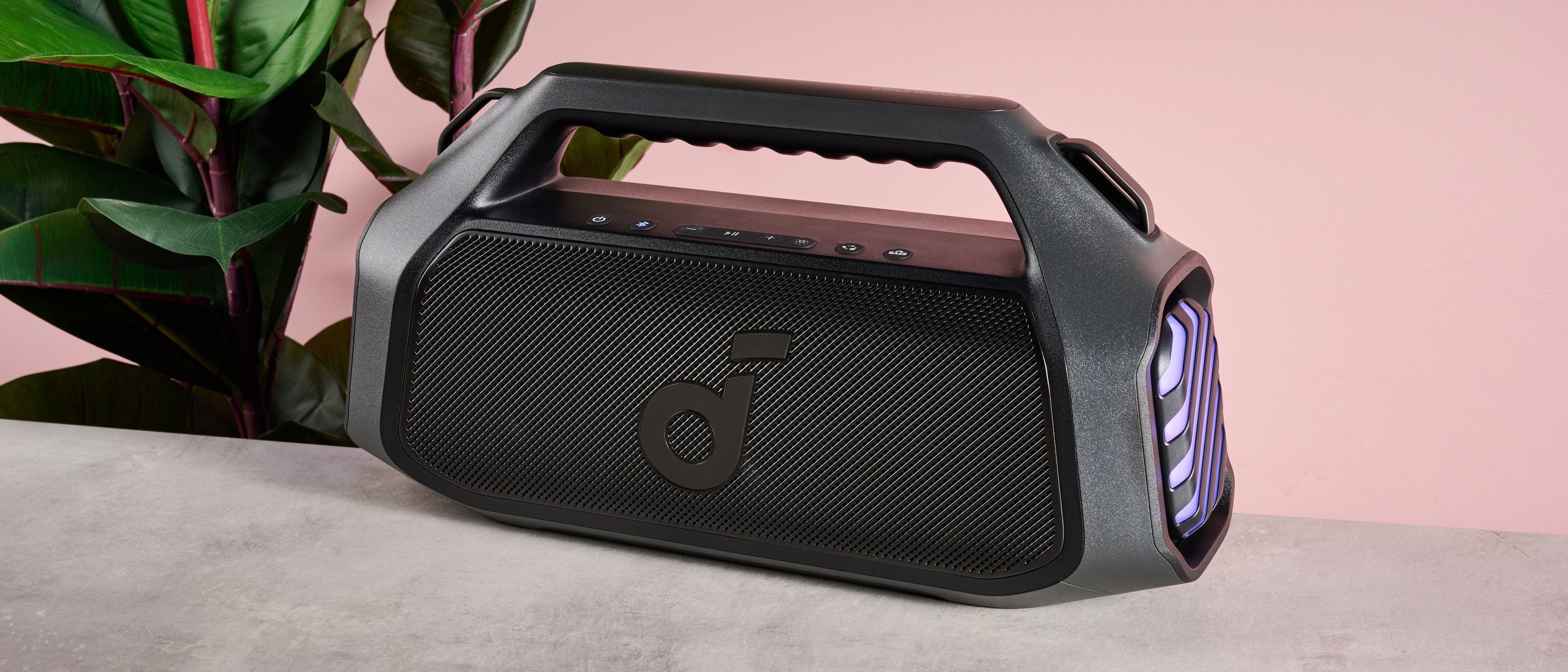 Anker Soundcore Boom 2 Plus next to plant on pink background