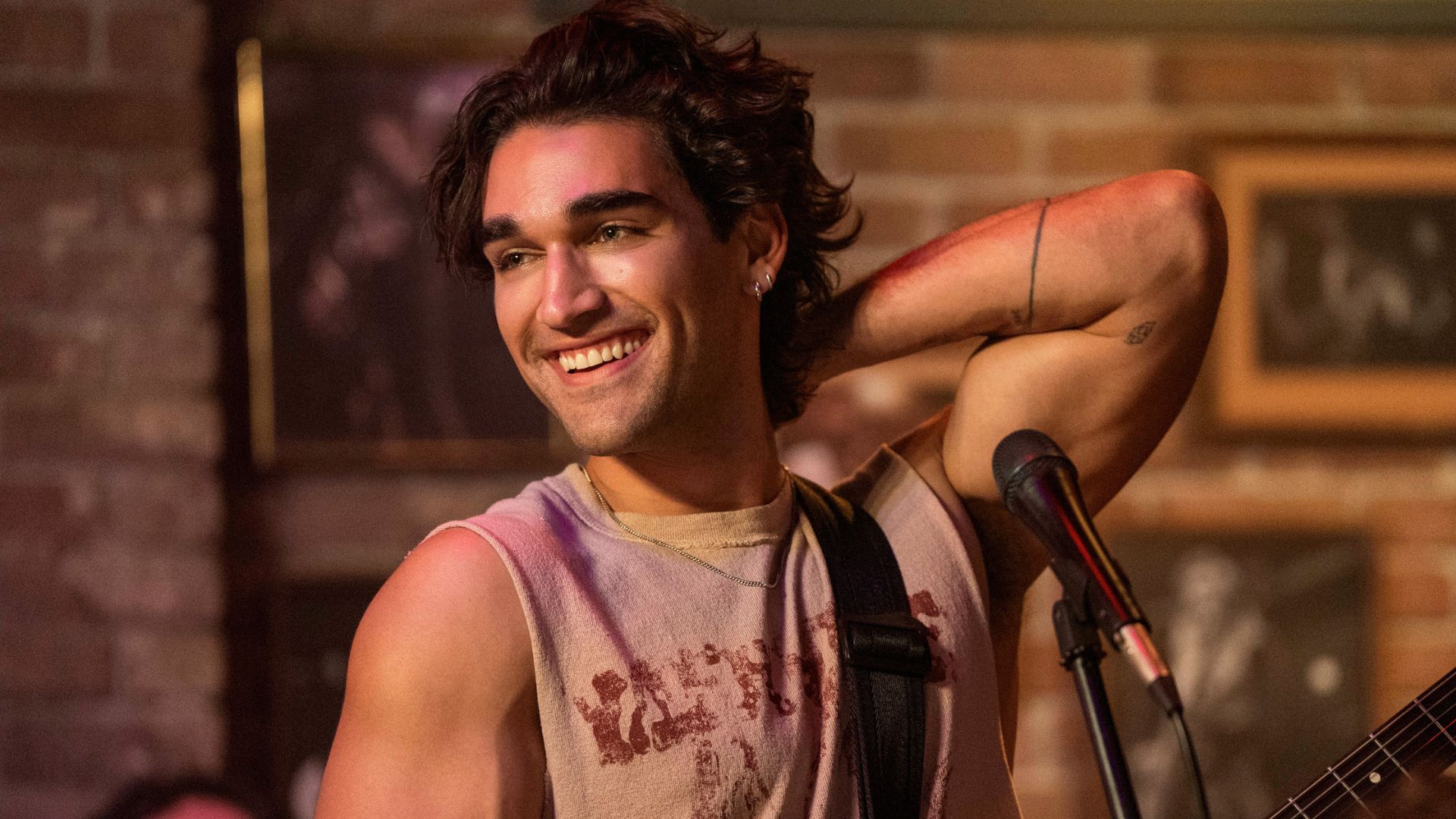 A young guitarist flexes his bicep on stage