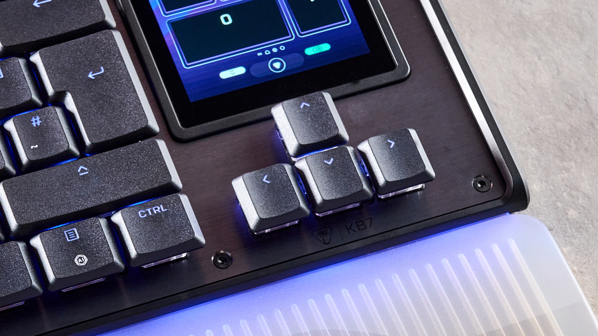 A closeup of the Turtle Beach Command Series KB7's arrow keys, with a small amount of the wrist rest and touchscreen visible.