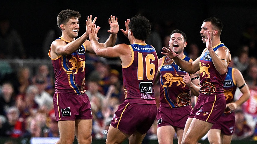 Zac Bailey of the Lions celebrates with team mates after kicking a goal during the round 18 AFL match between Brisbane Lions and Essendon Bombers at The Gabba.