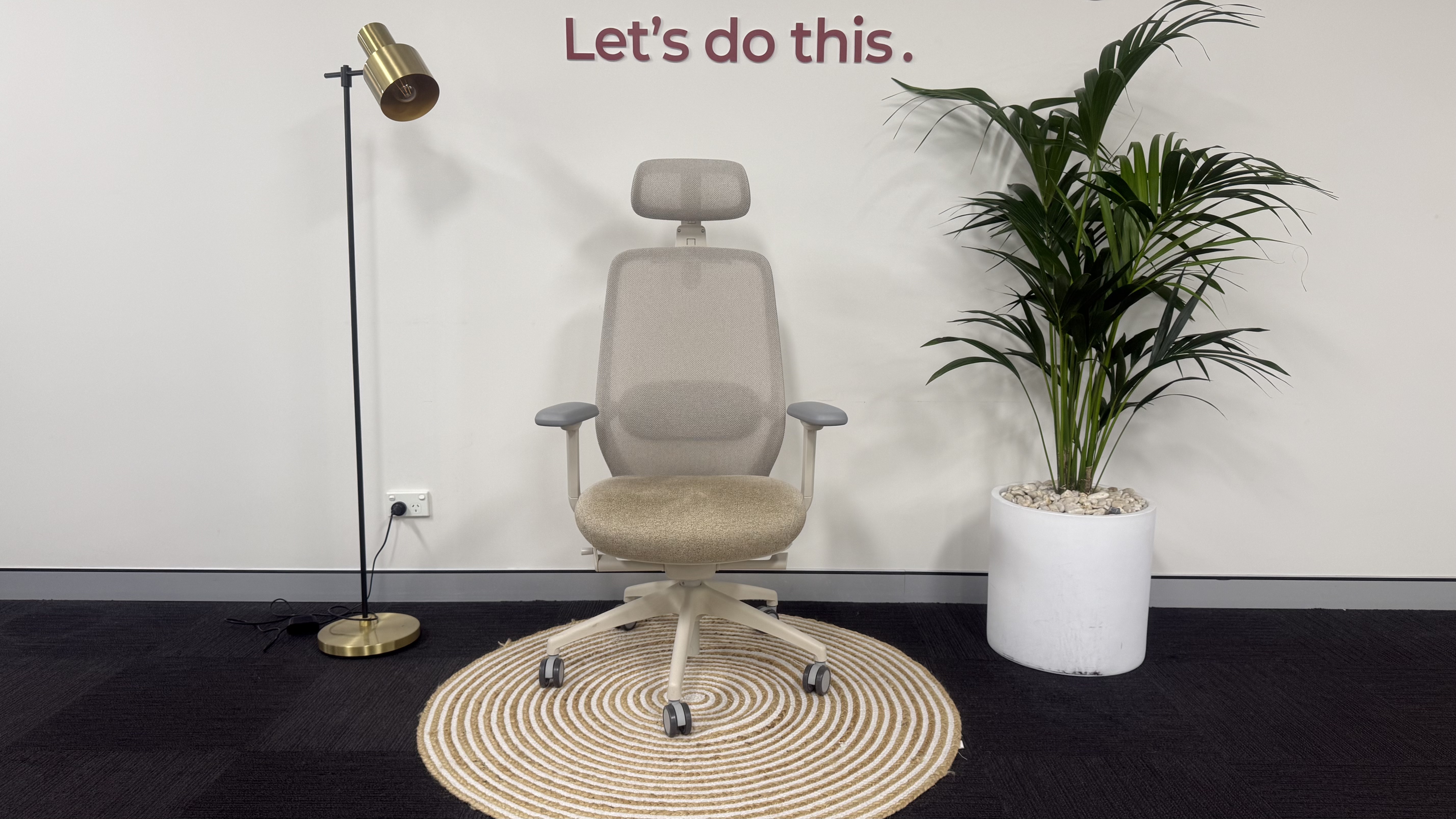 The Desky CoilFlex office chair on a rug next to a lamp and a plant