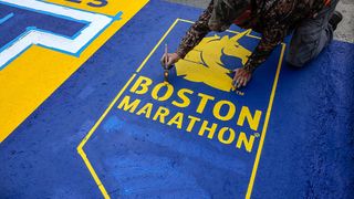 An employee of Mission Turf Services works on painting the starting line for the 129th Boston Marathon