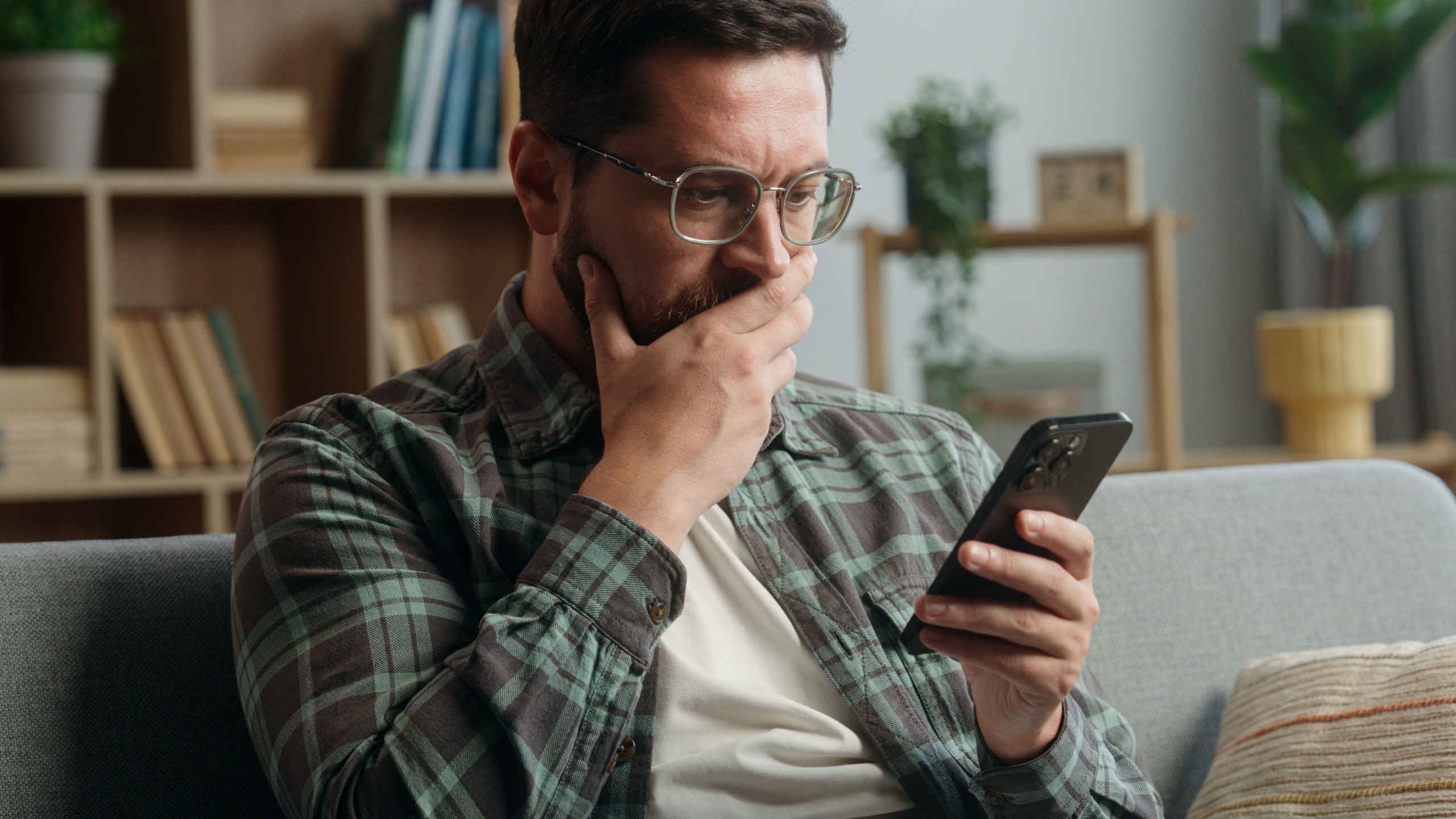 Caucasian adult man male guy at home living room nervous looking at mobile phone.
