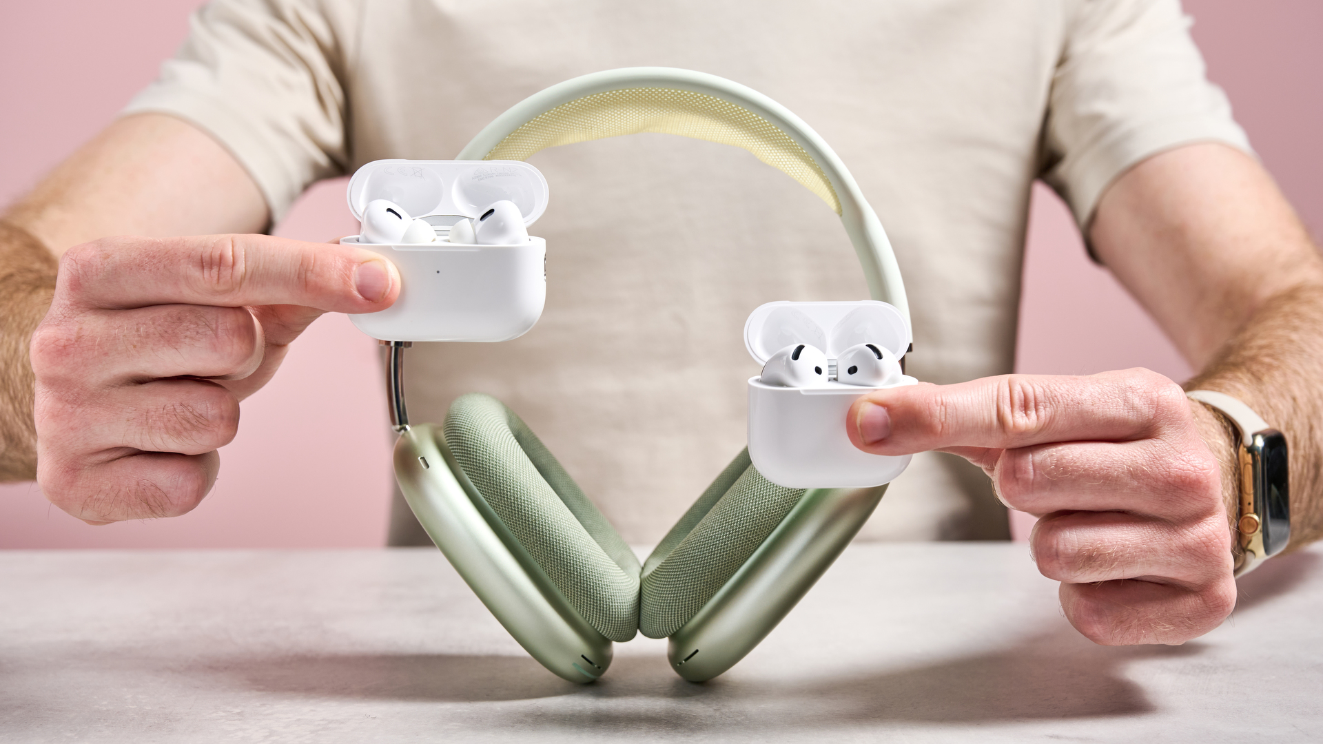 AirPods Pro 2, AirPods 4 and AirPods Max being held together in front of a man's torso
