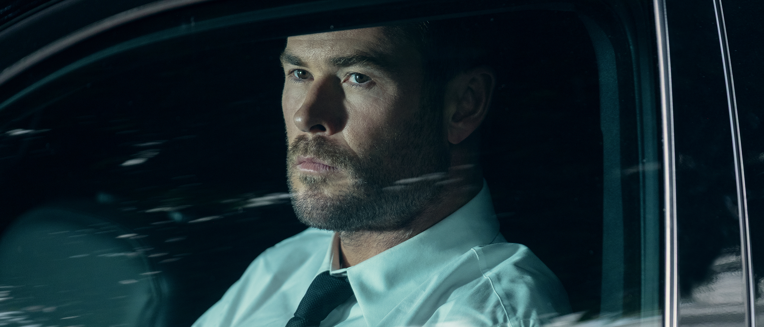Chris Hemsworth's Davis sitting in the driver's seat of a car in Crime 101
