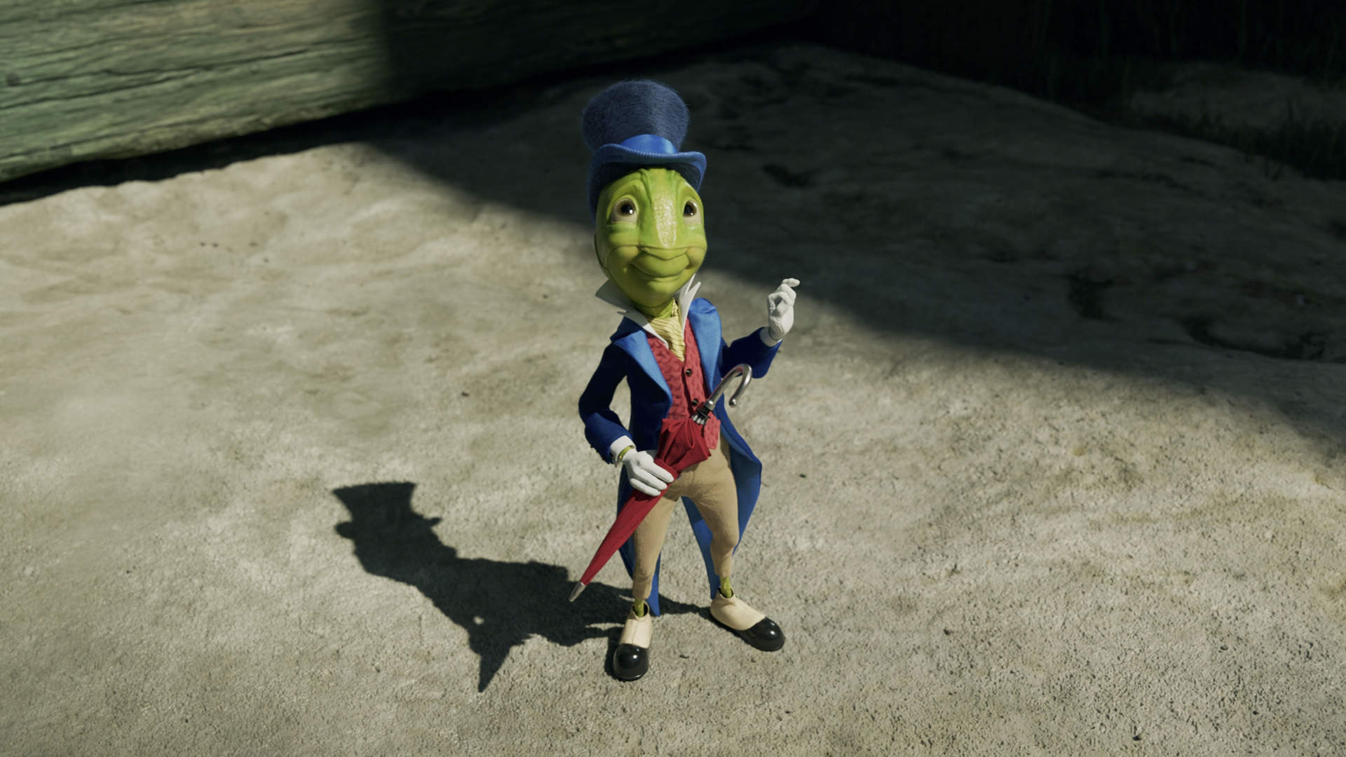 Jiminy Cricket smiles as he looks up at someone off screen in the sunshine in Disney's Pinocchio remake