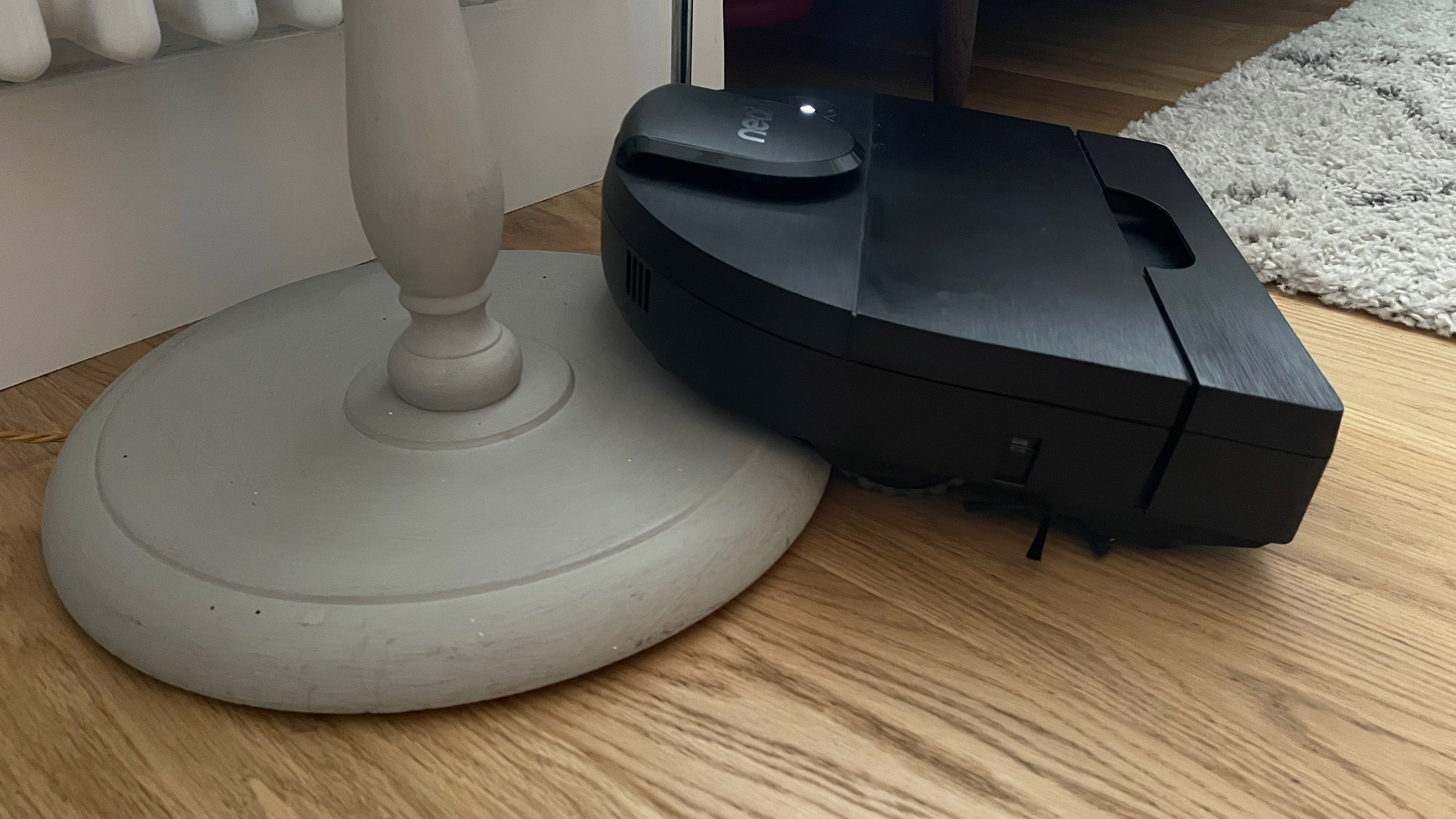 The Neato D9 attemtping to climb up the base of a floor lamp