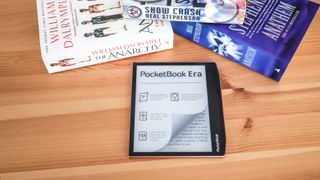 A PocketBook Era ereader on a table with some books and spectacles