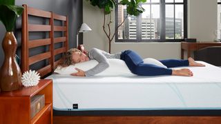 A person lying on a bed with the Tempur-Pedic BodyPillow