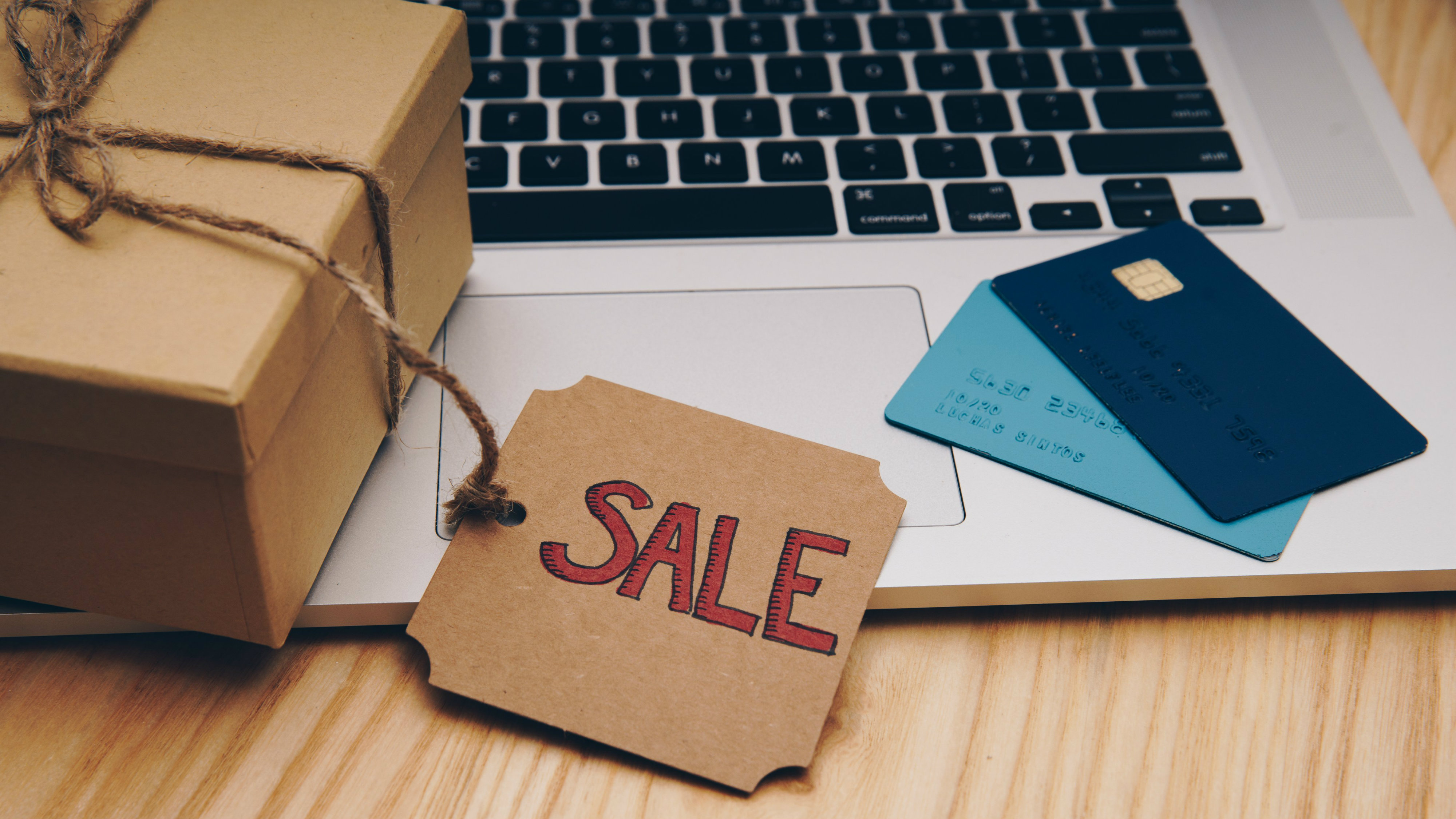 A 'sale' tag on a box placed on a laptop beside some credit cards