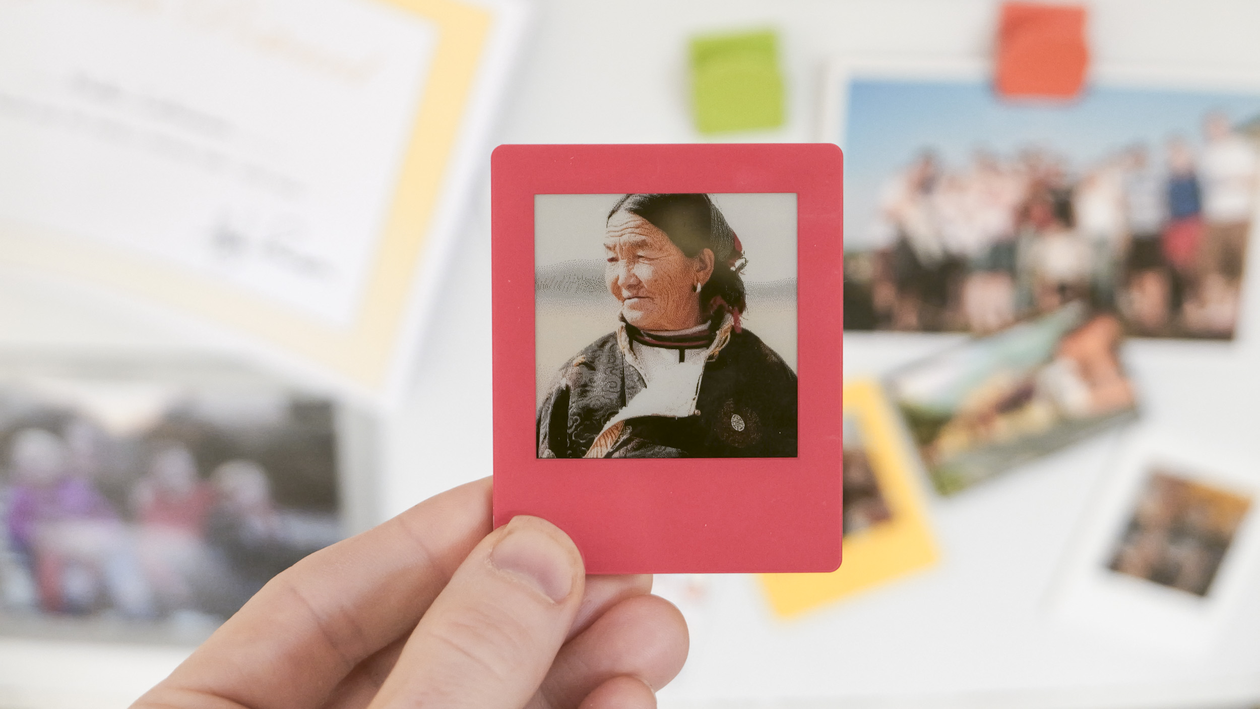 Vidabay Snap E Ink Polaroid-like frame held up in front of a fridge which is covered with pictures