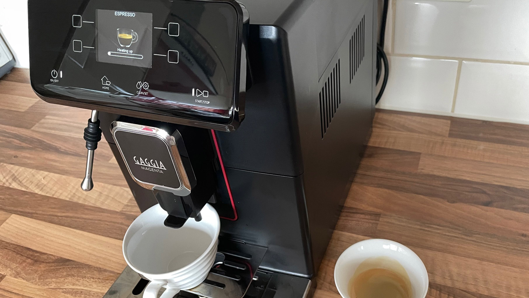The siode view of the Gaggia Magenta Plus while its ready to bew a second espresso, another espresso in a cup sits to the right-hand side