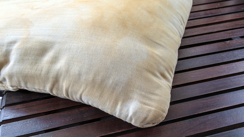 Corner of a dirty pillow on a wooden floor