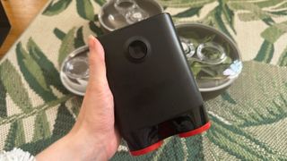 B!pod Dro!d held in a hand above a table with a floral green tablecloth on it