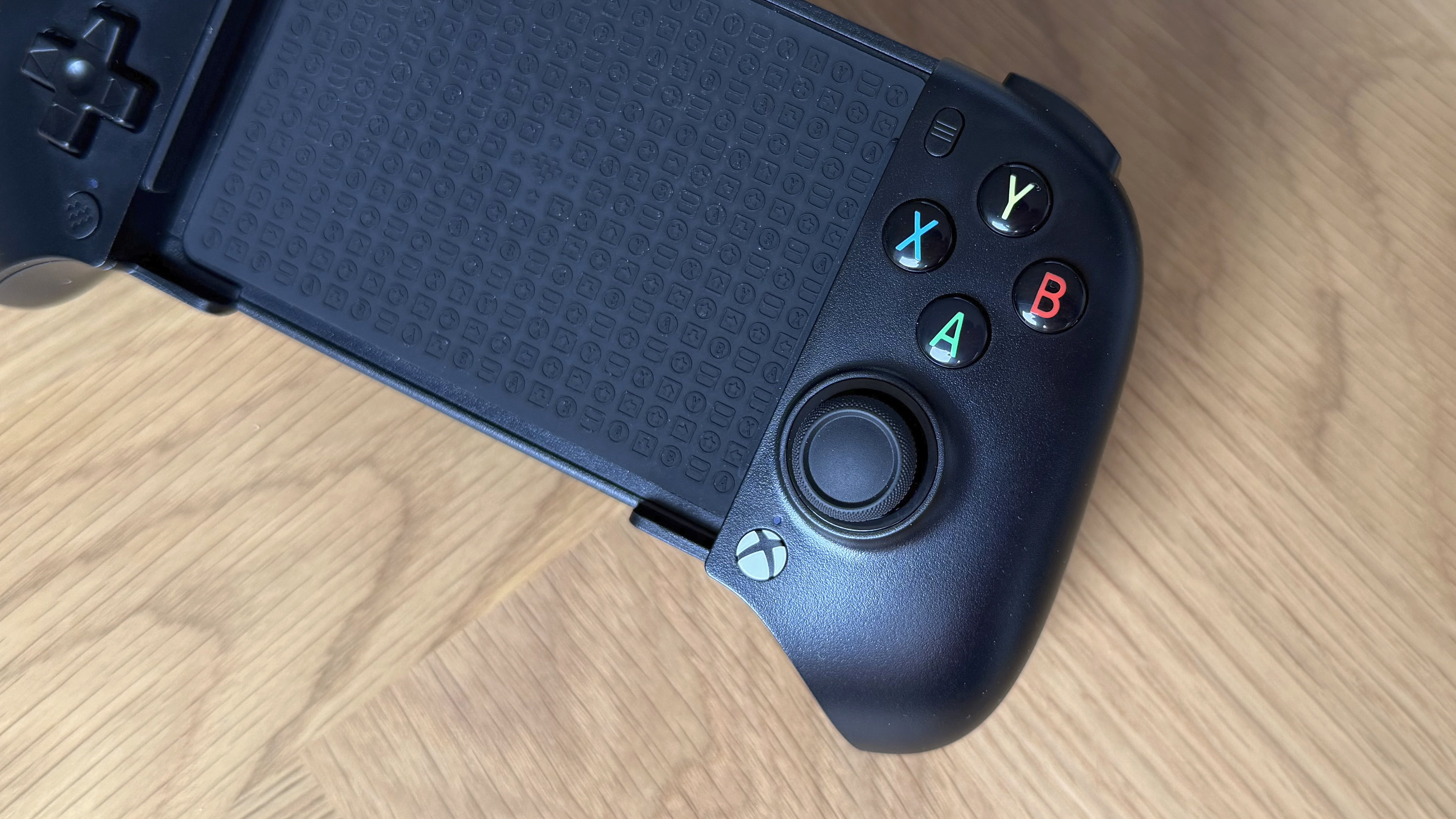 The 8BitDo Ultimate Mobile Gaming Controller - Xbox Edition with the background of a wooden surface.