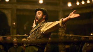 Daniel Mays wearing a bowler hat in a boxing ring with his arms outstretched