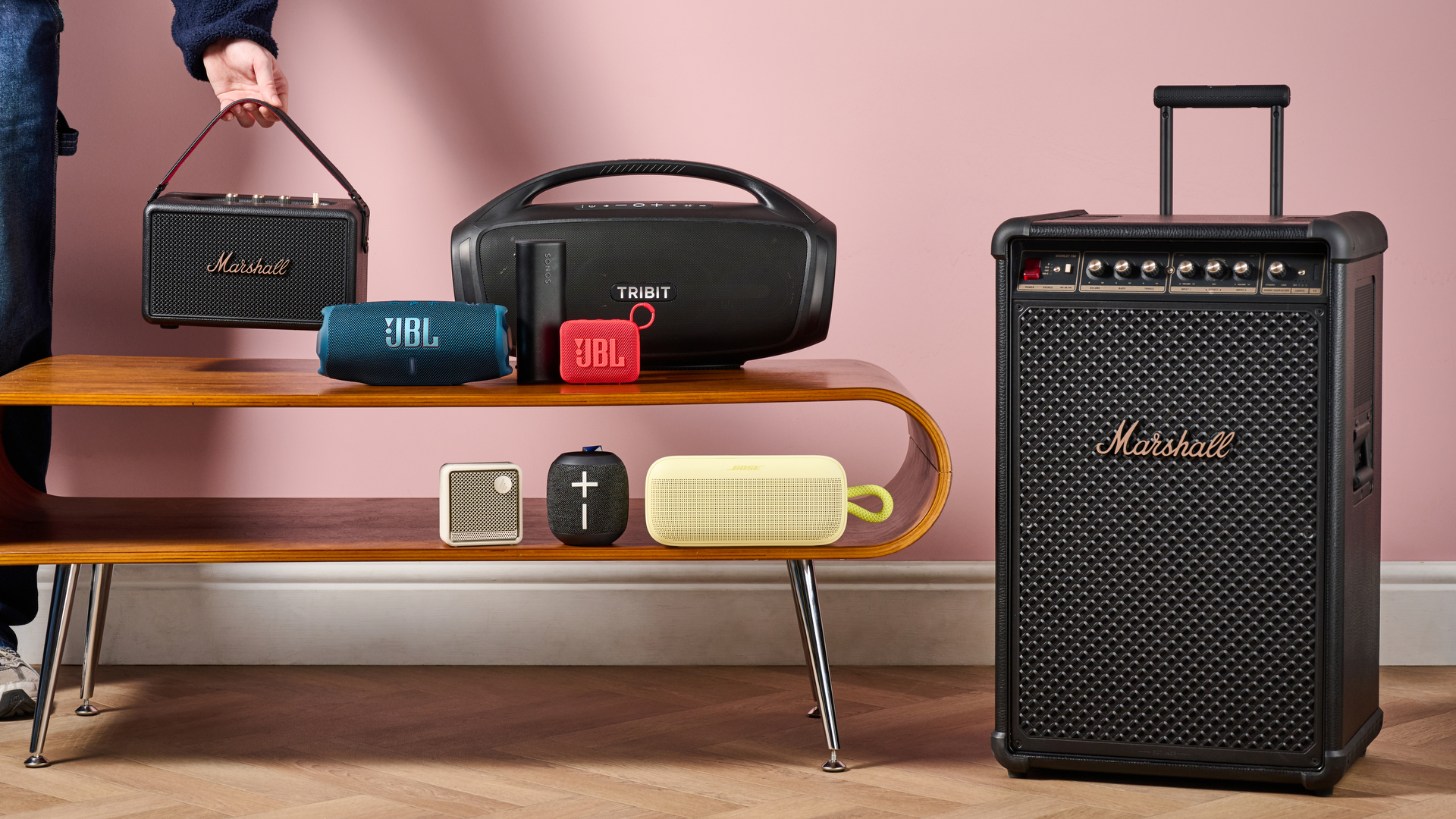 Man placing Marshall Kilburn III on table with a range of the best Bluetooth speakers