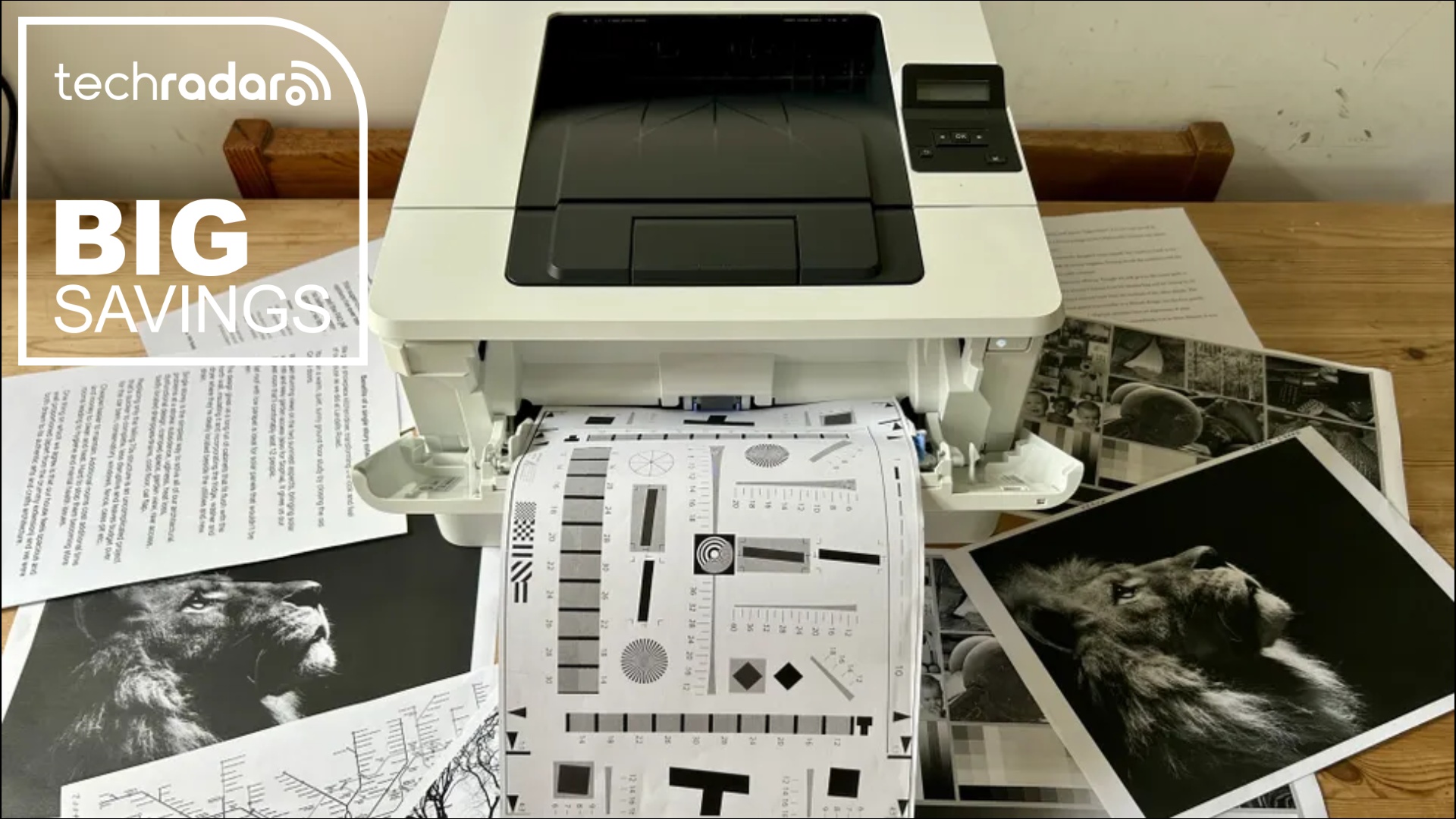 The HP LaserJet Pro 4001dn  with a  selection of mono print outs during our tests in a home office, next to a white TechRadar badge that reads 'Big Savings'