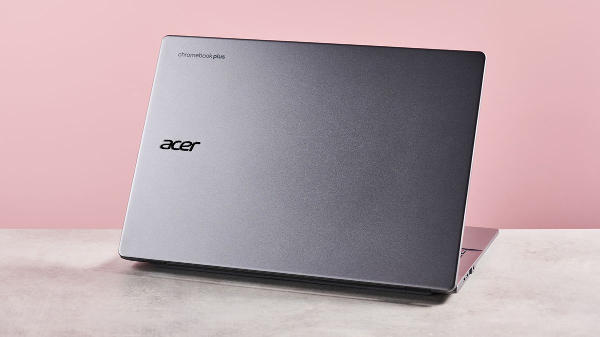 Back of Acer Chromebook Plus 514, on desk with pink background