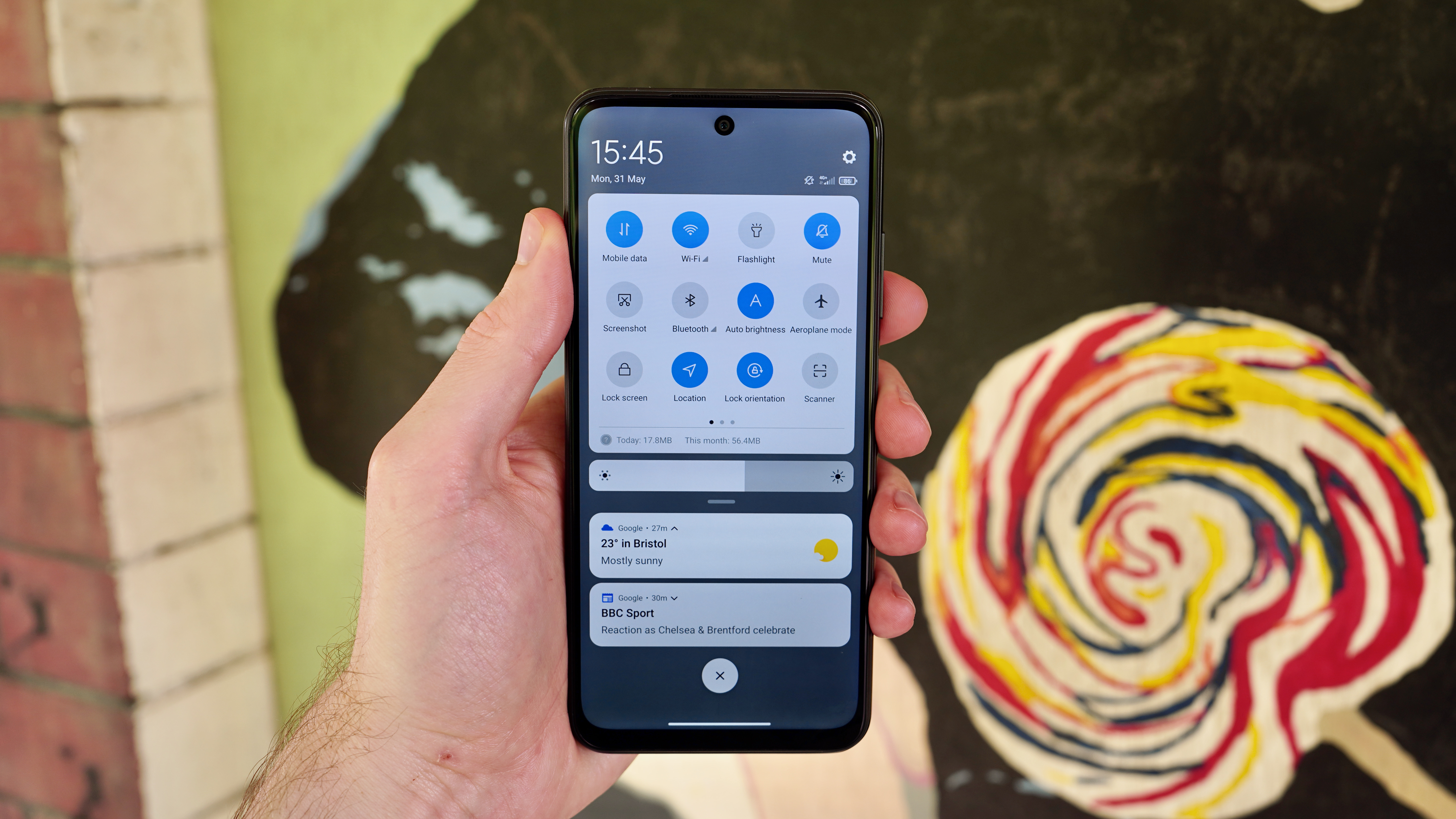 A Xiaomi Redmi Note 10 5G in someone's hand, displaying the quick settings screen