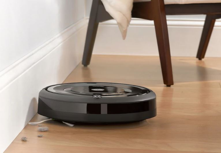 The irobot roomba e5 cleaning hard wood flooring with a chair in the background