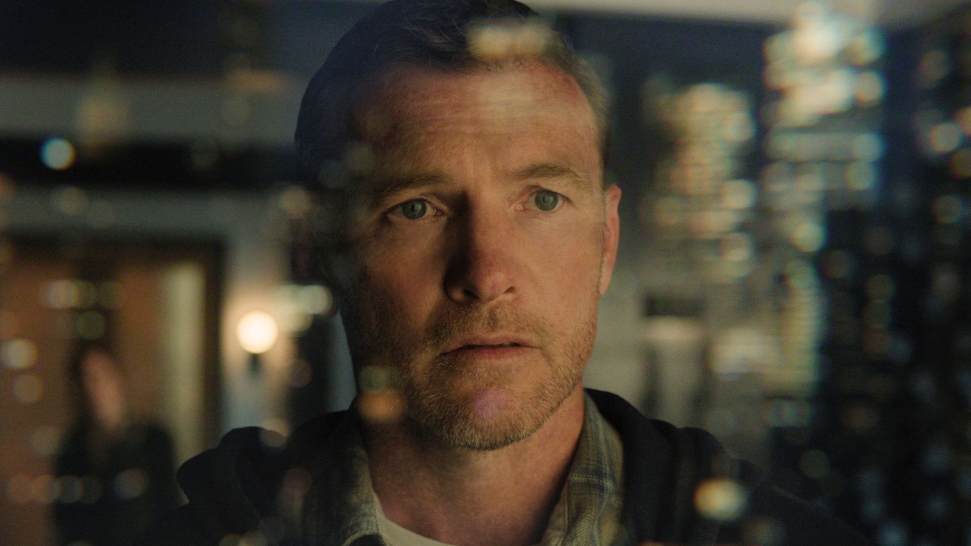 Sam Worthington looks out of a window