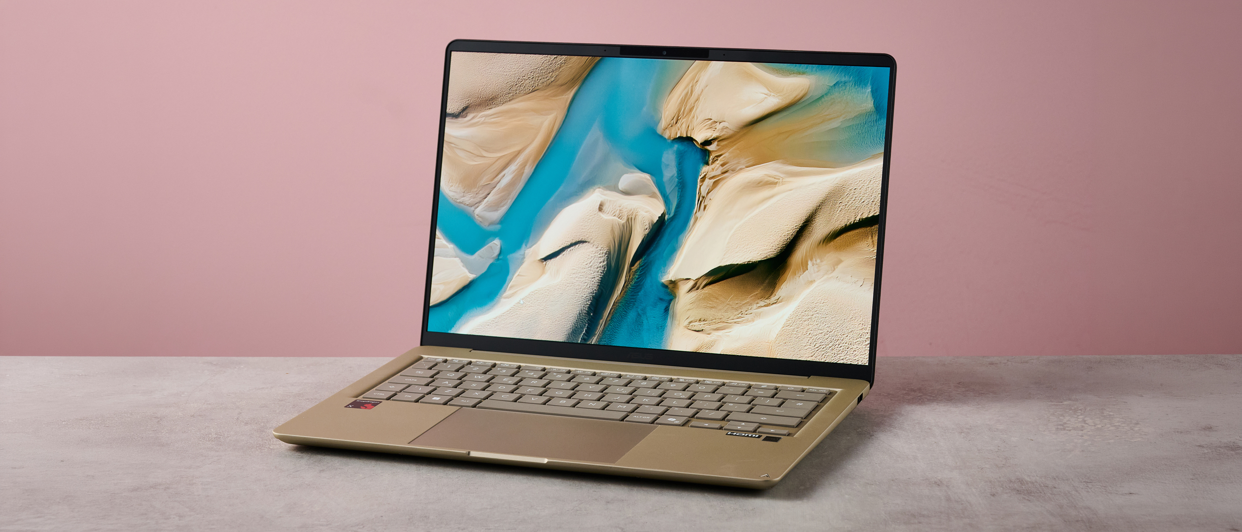 Three-quarter view of Asus Zenbook 14 2026 on a desk with pink wall in background