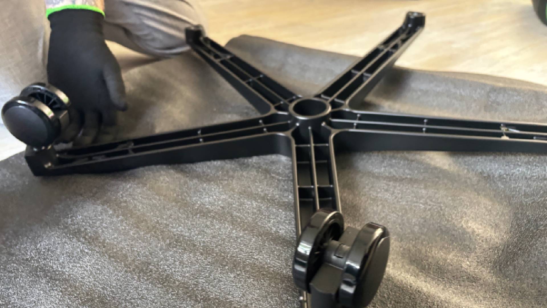 Razer Iskur V2 NewGen wheel base on a grey foam mat with two wheels on and a man in gloves assembling the base.